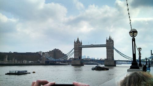 Tower bridge over thames river against cloudy sky in city