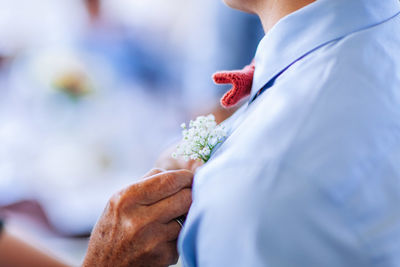 Cropped hand adjusting flowers on man shirt