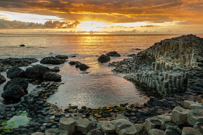 Stacked rocks at beach against sky during sunset