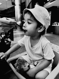 Cropped hand of person feeding boy at home