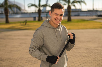 Young man holding camera while standing on road