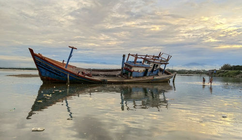 Boat in sea against sky during sunset