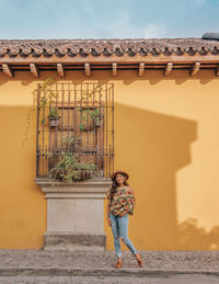 Portrait of woman standing against house