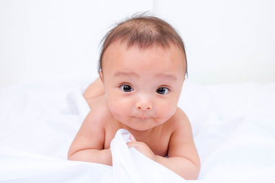 Close-up portrait of naked baby boy lying on bed