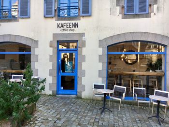 Chairs and tables at sidewalk cafe against buildings