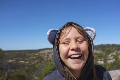 Portrait of smiling young woman against clear sky