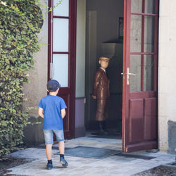 Rear view of boy standing by door of building