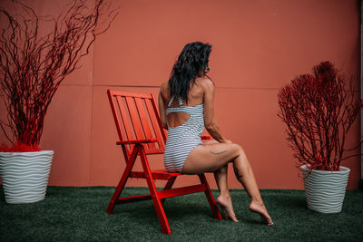 Woman sitting on chair against plants