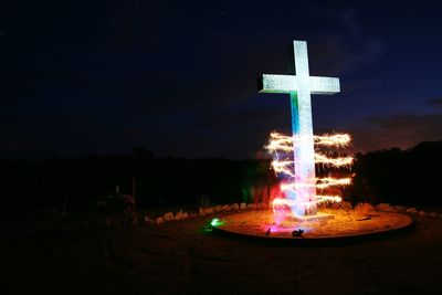 Illuminated cross against sky at night