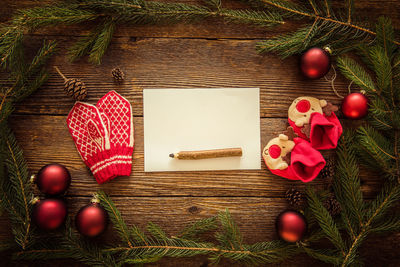 Directly above shot of pine needles with blank paper and pencil on wooden table