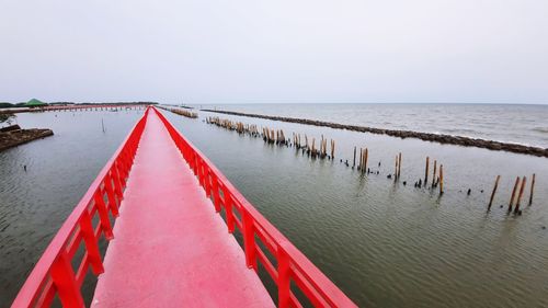 Wooden posts on pier over sea against clear sky