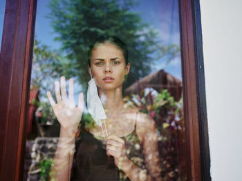 Portrait of young woman standing by window