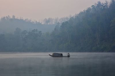 Boat moored on lake against forest