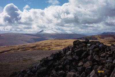 Scenic view of fell top cairn against sky with snowy blencathra in the distance