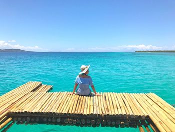 Rear view of woman relaxing on beach against blue sky