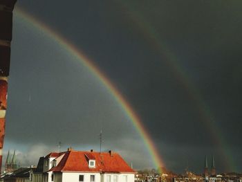 Rainbow over buildings in city against sky