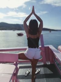 Rear view of woman standing by sea against sky