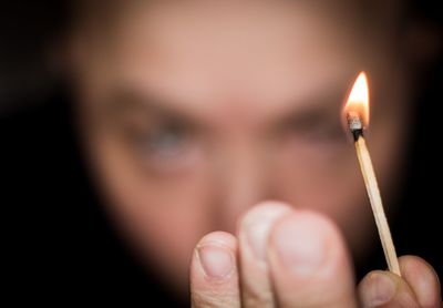 Close-up of hand holding burning candle