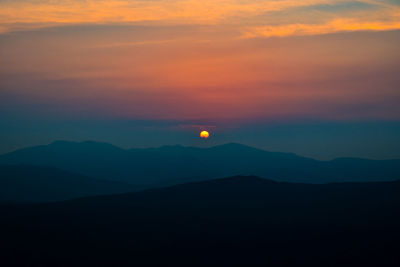 Scenic view of silhouette mountains against romantic sky at sunset