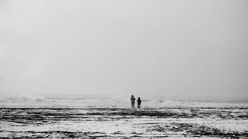 Silhouette people on sea against clear sky