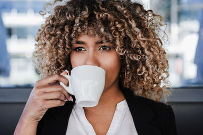 Confident hispanic afro business woman in cafe drinking coffee. business concept, lifestyle