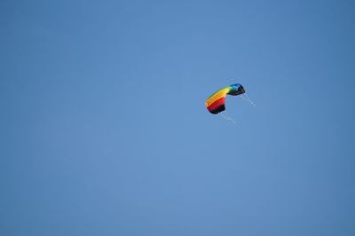 Low angle view of person paragliding against clear blue sky