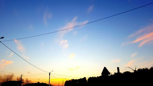 Low angle view of power lines against cloudy sky