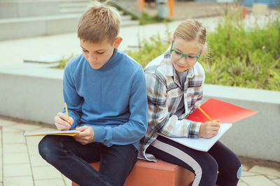 Rear view of father and son sitting on book