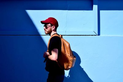 Young man walking by blue wall