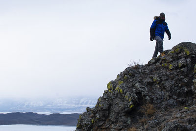 People on rock by mountain against sky