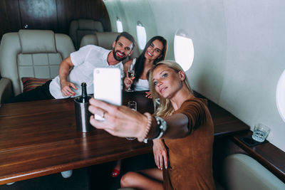 Friends taking selfie on phone in airplane