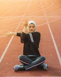 Female athlete stretching while sitting on track