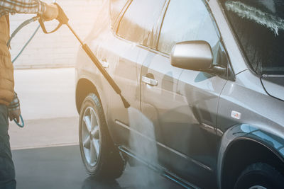 Midsection of man cleaning car in garage