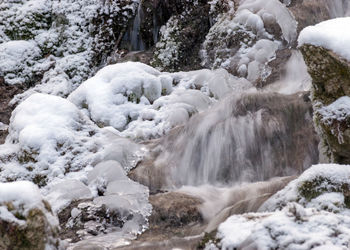 Contrasts of frozen and running water, spring water flows over pieces of limestone