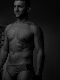 Shirtless man standing against black background