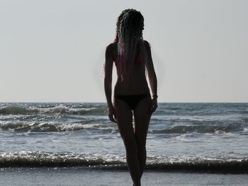 Full length of teenage girl standing at beach against sky