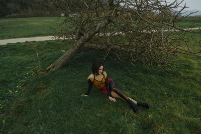 Young woman posing while sitting on field