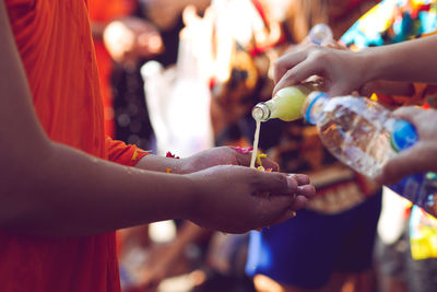 Cropped image of people pouring liquid into monk hands