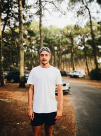 Portrait of young man standing against trees