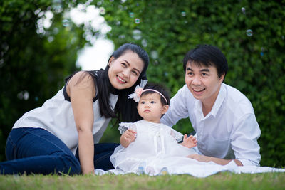Friends sitting on grassland against plants