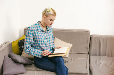 Young woman sitting on sofa at home