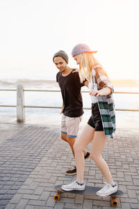 Young woman skateboarding against sea