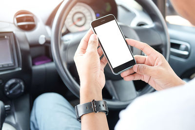 Cropped hand of woman using mobile phone while driving car