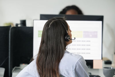 Rear view of woman sitting at desk with headset on