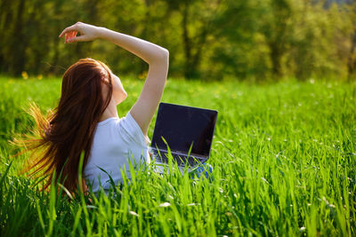 Rear view of woman sitting on grassy field