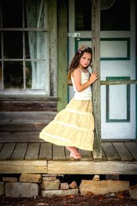 Portrait of young woman standing against wall