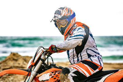 Side view of man riding motorcycle on sea shore