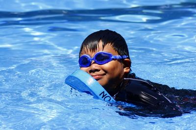 Side view of boy with kickboard in swimming pool