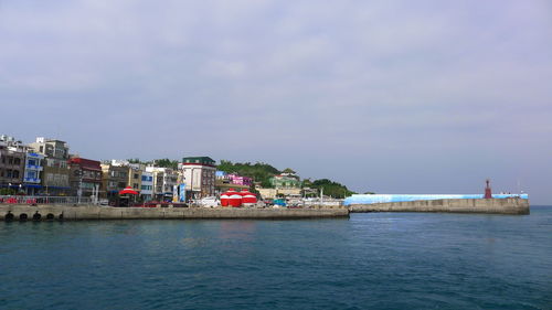 Buildings by sea against sky