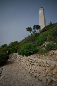 Lighthouse by sea against clear sky